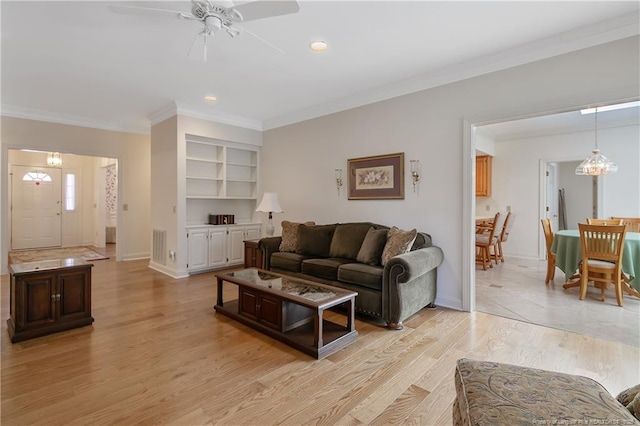 living room featuring light wood-type flooring, ceiling fan with notable chandelier, and ornamental molding