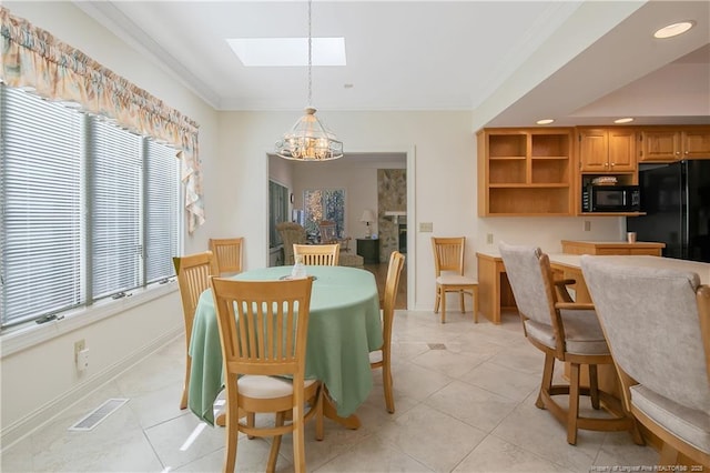 dining area with light tile patterned flooring, an inviting chandelier, crown molding, and a skylight