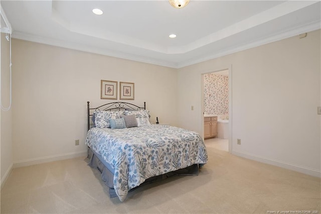 bedroom with a raised ceiling, ornamental molding, light carpet, and ensuite bath