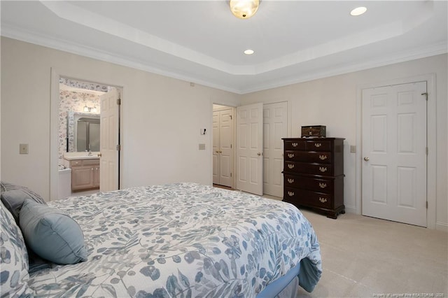 carpeted bedroom featuring a tray ceiling, ensuite bathroom, sink, and ornamental molding