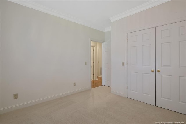 unfurnished bedroom with crown molding, a closet, and light carpet