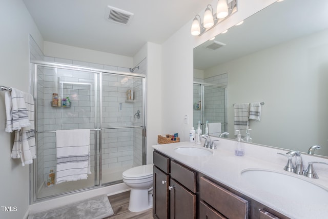 bathroom with hardwood / wood-style floors, vanity, toilet, and walk in shower