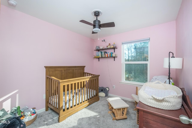 carpeted bedroom featuring ceiling fan and a crib