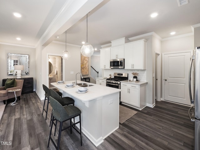 kitchen featuring stainless steel appliances, decorative light fixtures, dark hardwood / wood-style floors, white cabinetry, and an island with sink