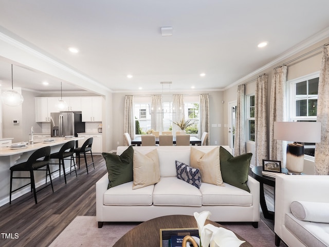 living room featuring dark hardwood / wood-style flooring, a notable chandelier, and ornamental molding