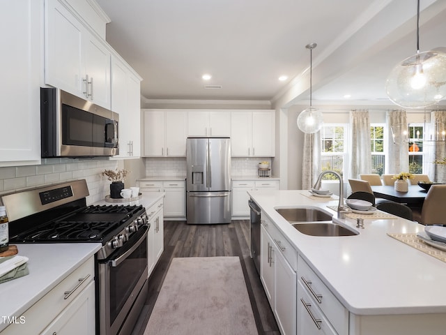 kitchen featuring a kitchen island with sink, sink, hanging light fixtures, white cabinetry, and stainless steel appliances