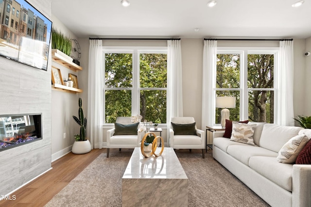 living room with plenty of natural light, a tiled fireplace, and light hardwood / wood-style flooring