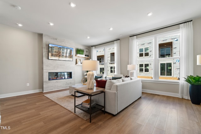 living room with a fireplace and light wood-type flooring