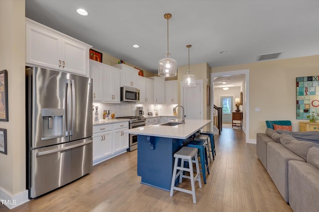 kitchen featuring white cabinetry, sink, a breakfast bar area, hanging light fixtures, and stainless steel appliances