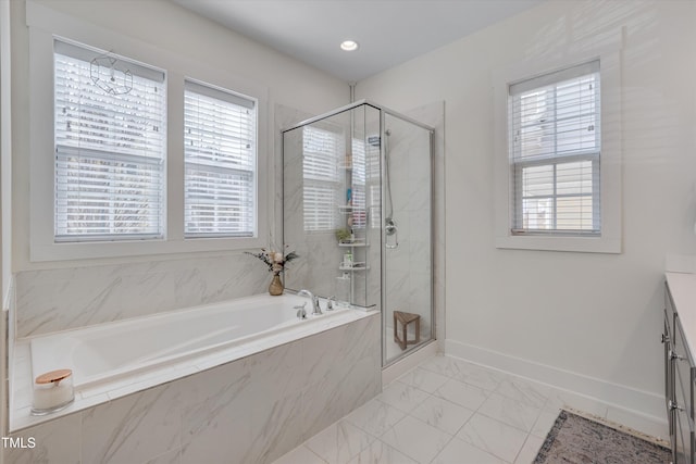 bathroom with plus walk in shower, a healthy amount of sunlight, and vanity