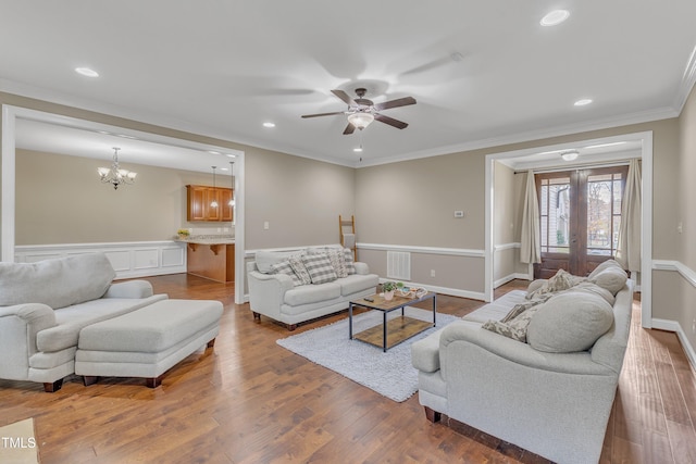 living room with hardwood / wood-style flooring, ceiling fan with notable chandelier, ornamental molding, and french doors