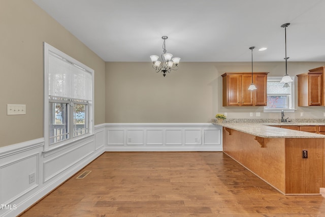 kitchen featuring kitchen peninsula, pendant lighting, a breakfast bar, and a healthy amount of sunlight