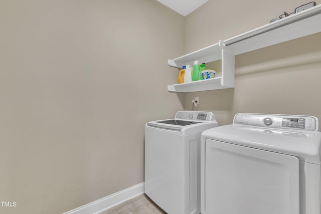 clothes washing area featuring washer and clothes dryer and light tile patterned floors