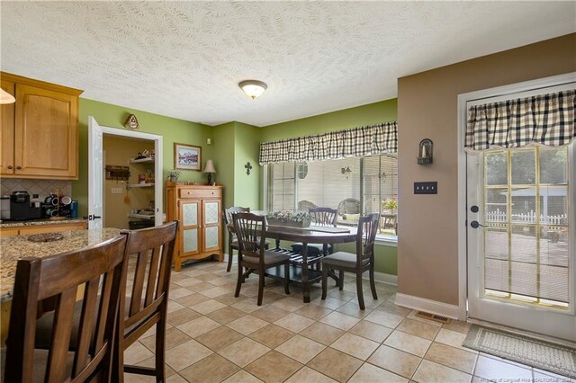 tiled dining space featuring a textured ceiling