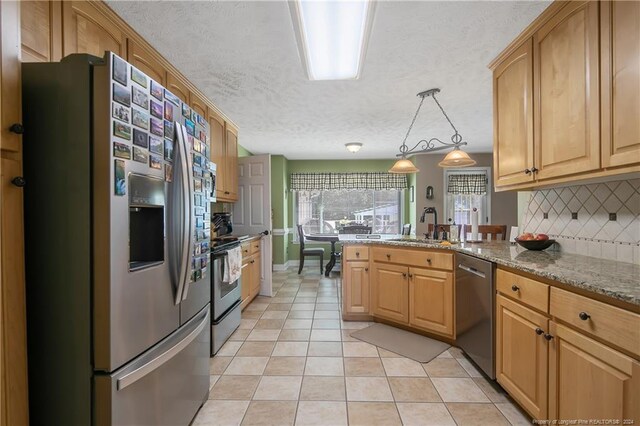 kitchen featuring pendant lighting, decorative backsplash, a textured ceiling, appliances with stainless steel finishes, and light stone counters