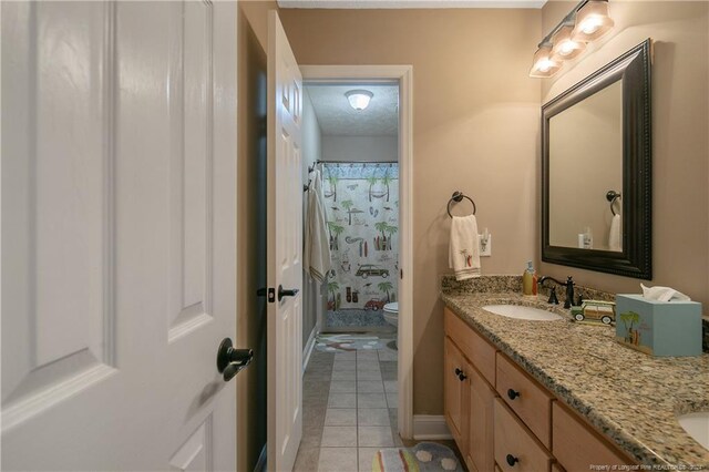 bathroom featuring tile patterned floors, walk in shower, vanity, and toilet