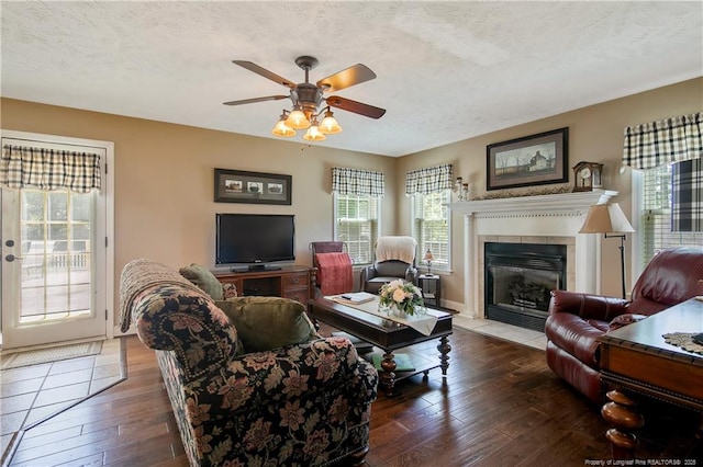 living area with hardwood / wood-style flooring, a ceiling fan, a textured ceiling, and a fireplace