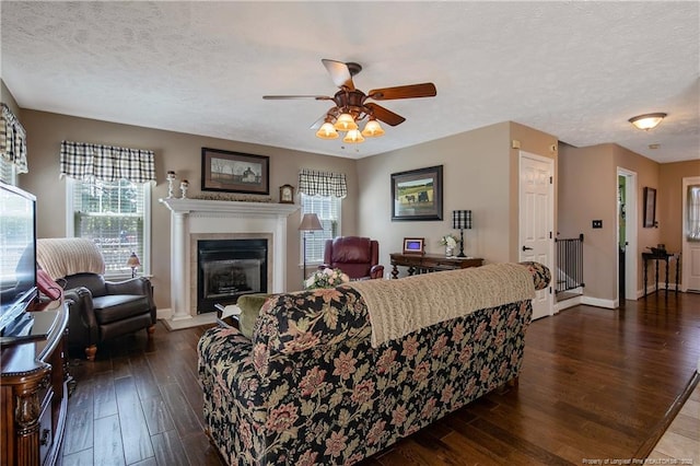 living area featuring a textured ceiling, ceiling fan, baseboards, and dark wood-type flooring