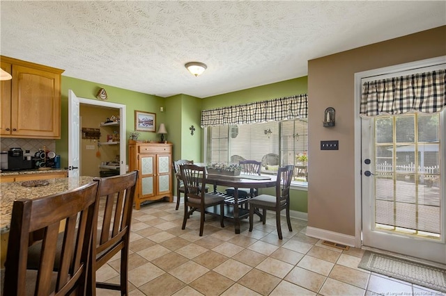 dining room with baseboards, visible vents, a textured ceiling, and light tile patterned flooring
