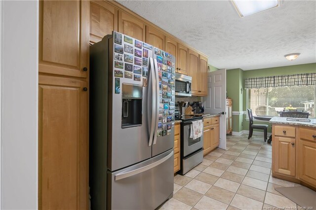 4402 Bluebush Dr, Fayetteville, NC 28312 - kitchen featuring light stone countertops, light tile patterned floors, stainless steel appliances, baseboards, and a textured ceiling