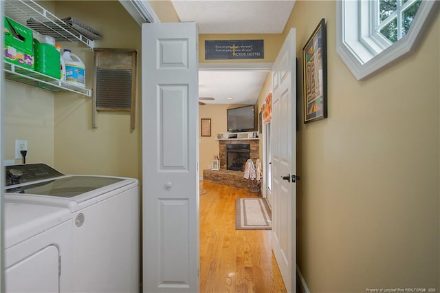 laundry area featuring a fireplace, washer and clothes dryer, light wood-style flooring, and laundry area