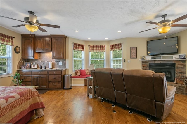 bedroom with a fireplace, recessed lighting, a textured ceiling, and light wood-style floors