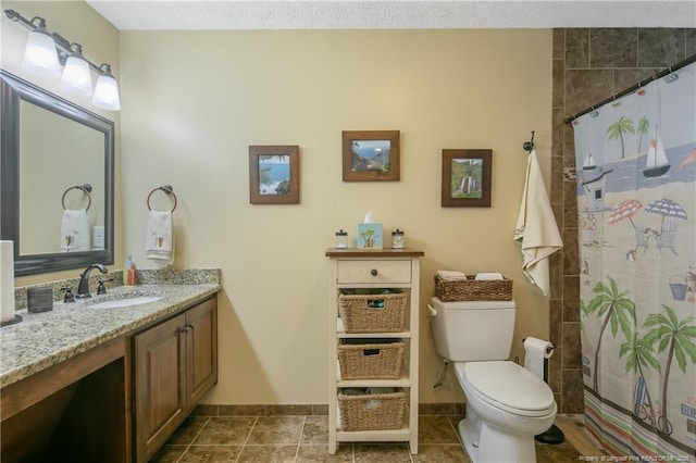 bathroom featuring vanity, toilet, a tile shower, and baseboards