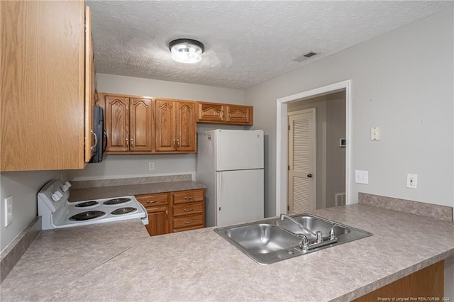 kitchen featuring a textured ceiling, kitchen peninsula, sink, and white appliances