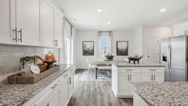 6433 Alfalfa Ln, Wake Forest, NC 27587 - kitchen with stainless steel refrigerator with ice dispenser, wood finished floors, white cabinets, backsplash, and light stone counters