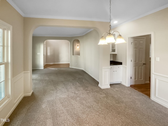 unfurnished room featuring carpet flooring, crown molding, and an inviting chandelier