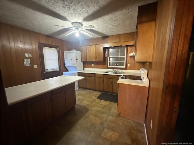 kitchen featuring ceiling fan, sink, a textured ceiling, wooden walls, and range