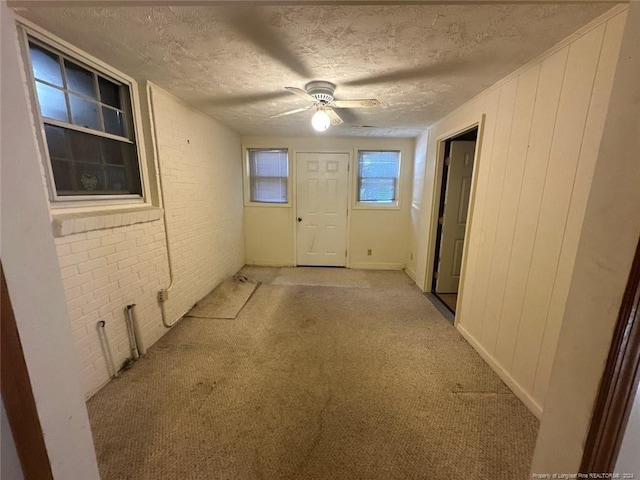 interior space with ceiling fan, brick wall, and a textured ceiling