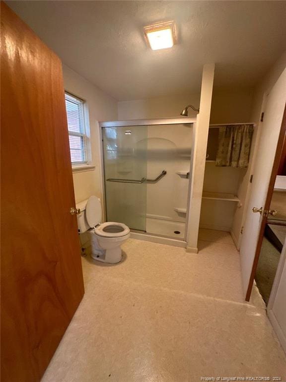 bathroom with a shower with door and toilet