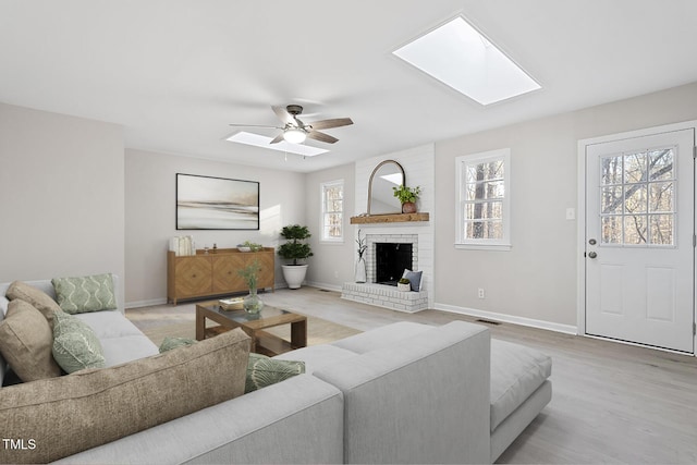 living room with a fireplace, light hardwood / wood-style floors, plenty of natural light, and ceiling fan