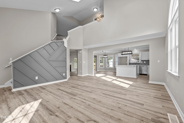 unfurnished living room featuring light wood-type flooring, high vaulted ceiling, and sink