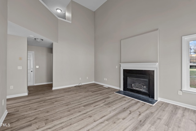 unfurnished living room featuring a high ceiling and light hardwood / wood-style flooring