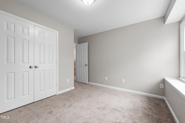 unfurnished bedroom featuring a closet and light colored carpet