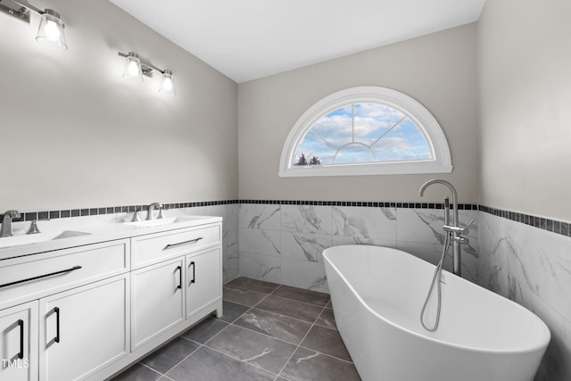 bathroom featuring a washtub, vanity, tile walls, and tile patterned flooring