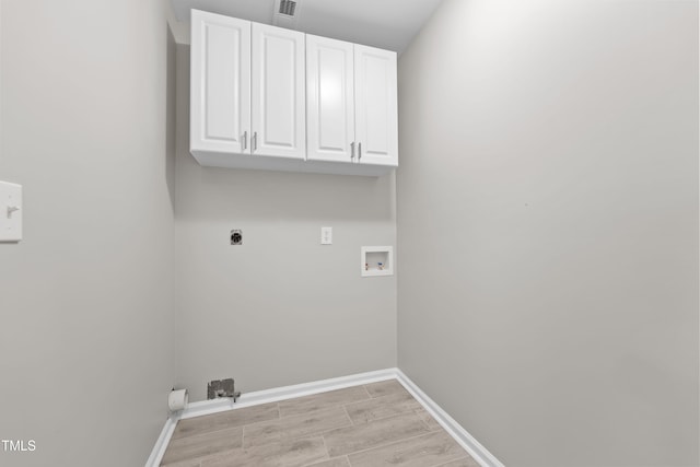 washroom featuring electric dryer hookup, hookup for a washing machine, cabinets, and light hardwood / wood-style flooring