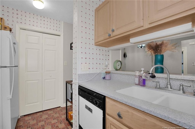 kitchen with light stone counters, sink, white appliances, and light brown cabinets