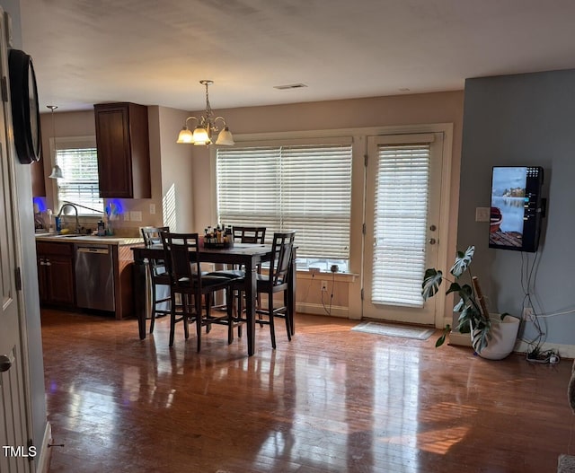 dining space with dark hardwood / wood-style flooring, sink, and an inviting chandelier