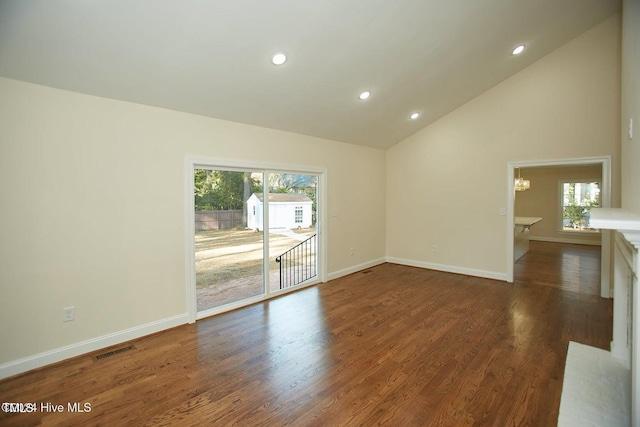 spare room featuring a wealth of natural light, dark wood-type flooring, and an inviting chandelier