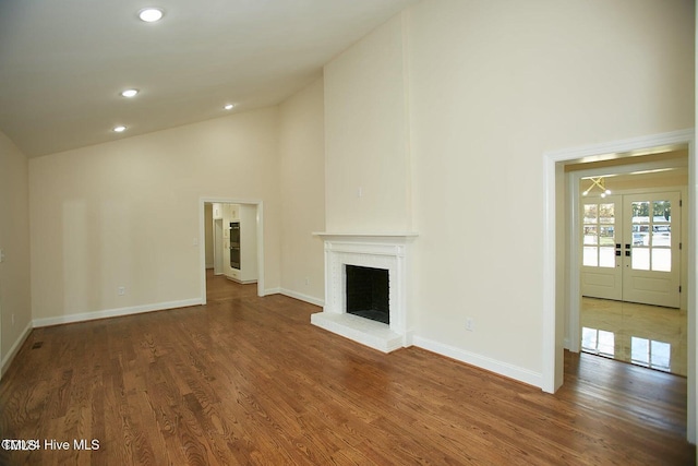 unfurnished living room featuring dark hardwood / wood-style flooring, high vaulted ceiling, and french doors