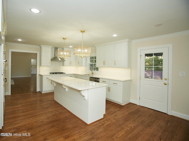 kitchen featuring decorative light fixtures, white cabinetry, a kitchen island, and wall chimney exhaust hood