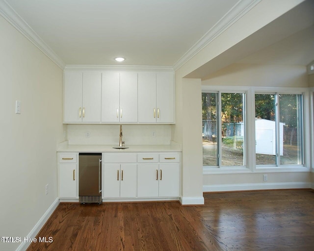 bar with crown molding, sink, white cabinets, and dark wood-type flooring