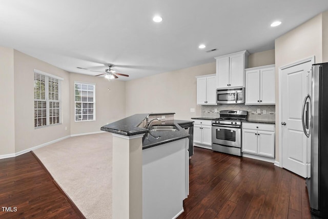 kitchen featuring appliances with stainless steel finishes, sink, white cabinetry, dark stone counters, and dark hardwood / wood-style floors