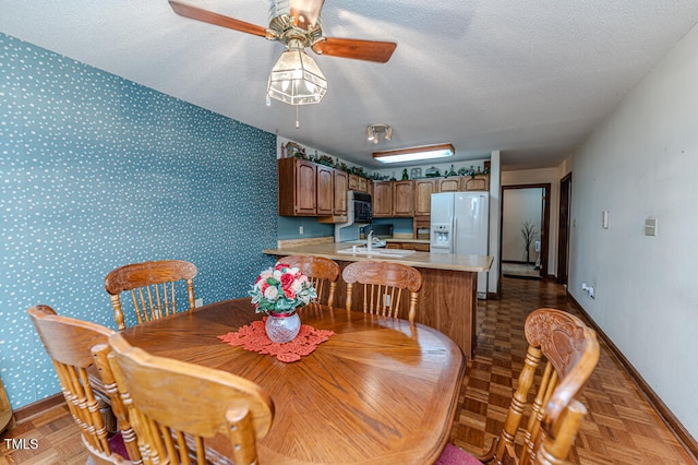 dining area featuring parquet flooring, a textured ceiling, ceiling fan, and sink