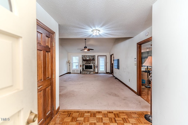 unfurnished living room featuring ceiling fan, light colored carpet, lofted ceiling, and a textured ceiling