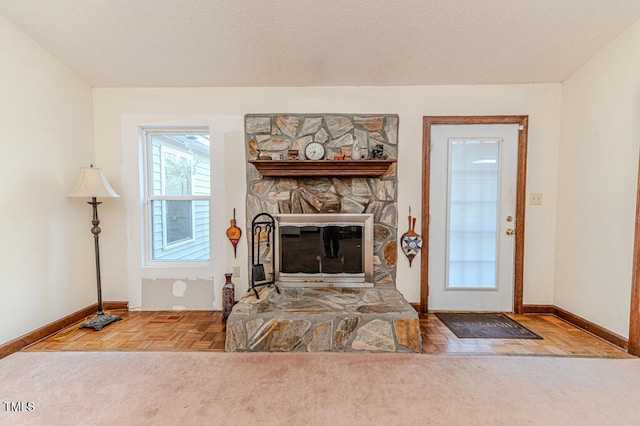 living room with a stone fireplace, parquet floors, and a textured ceiling