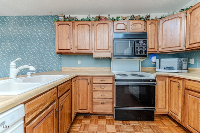 kitchen featuring a textured ceiling, sink, light parquet flooring, and black appliances